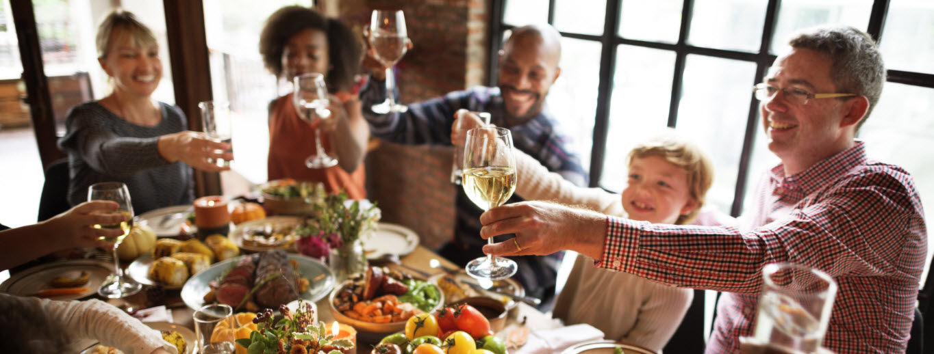 Family gathered for Thanksgiving dinner, smiling and talking around a decorated table.
